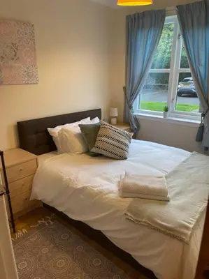 a bedroom with a bed with pillows and a window at 2 bed city centre modern flat in Edinburgh