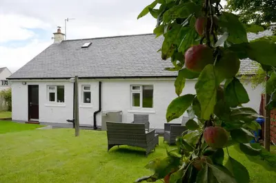 a white house with a bench in a yard at Ardview Cottage in Oban