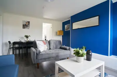 a living room with a couch and a blue wall at Dunalastair Apartment in Glasgow