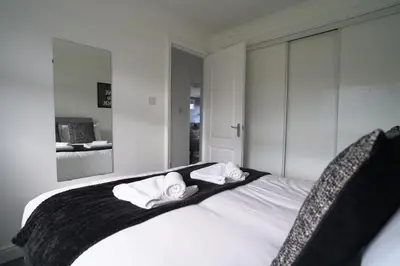 a bedroom with a white bed with towels on it at Dunalastair Apartment in Glasgow