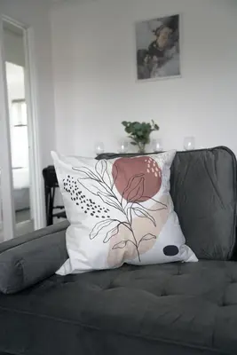 a pillow on a couch with a flower on it at Dunalastair Apartment in Glasgow