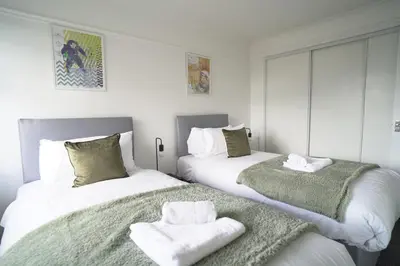 two beds in a room with towels on them at Dunalastair Apartment in Glasgow