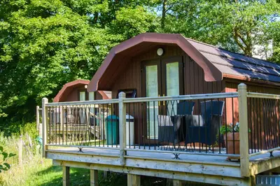 a small cabin with a porch and a fence at Heart of Glencoe Holidays in Glencoe