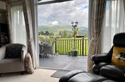 a living room with a sliding glass door to a deck at Honeycomb Lodge in Dollar