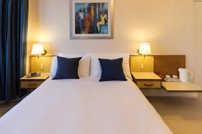 a bedroom with a large white bed with blue pillows at The Cedars Guest House in Dunoon