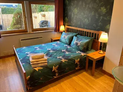 a bedroom with a bed with a blue comforter at Annexe Lodge cottage in Drymen in Drymen