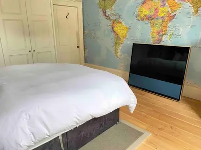 a bedroom with a bed and a flat screen tv at Home of Joy - 3 bedroom home with private garden in Glasgow