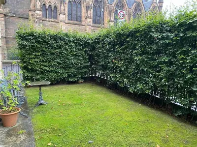 a hedge in front of a building with a bench at Home of Joy - 3 bedroom home with private garden in Glasgow