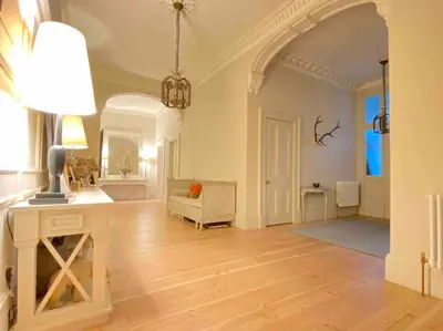 a large living room with a table and a chair at Home of Joy - 3 bedroom home with private garden in Glasgow