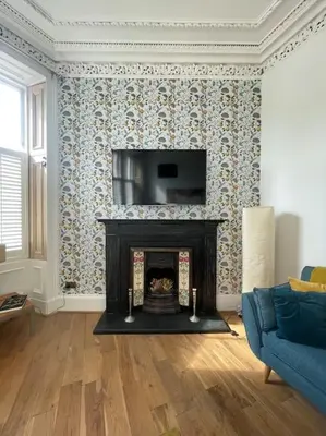 a living room with a fireplace and a blue couch at Stunning West End Flat! in Glasgow
