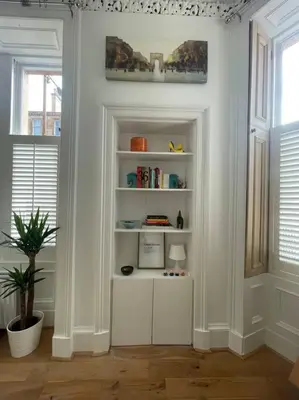 a white room with a book shelf and two windows at Stunning West End Flat! in Glasgow