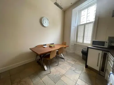 a kitchen with a table and a clock on the wall at Stunning West End Flat! in Glasgow