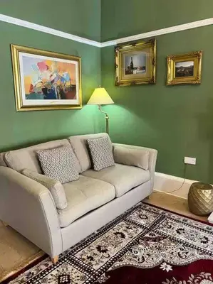 a living room with a couch and a green wall at Luxury Victorian spacious flat in Glasgow