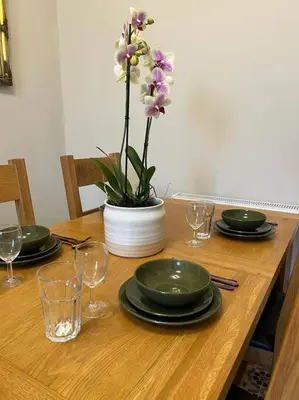 a table with plates and glasses and a vase with flowers at Luxury Victorian spacious flat in Glasgow