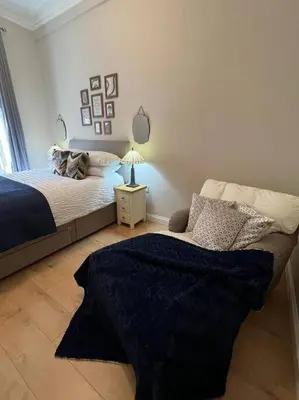 a bedroom with a bed and a table with a lamp at Luxury Victorian spacious flat in Glasgow