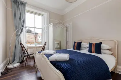 a bedroom with a bed and a desk and a window at Stylish Victorian Apartment's close to the Botanical gardens, Free parking! in Edinburgh