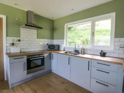 a kitchen with white cabinets and a window at Beech Cottage in Aberfeldy