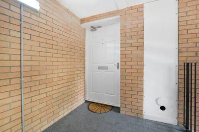 a brick wall with a white door in a brick building at PREMIER - Clydesdale Apartment in Mossend
