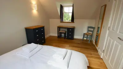a bedroom with a white bed and a wooden floor at Edinample Lodge in Lochearnhead