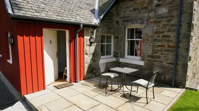 a patio with a table and chairs next to a building at Edinample Lodge in Lochearnhead