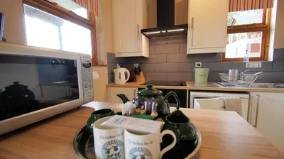 a kitchen with a table with mugs and a microwave at Morenish Mews Killin Cottage in Morenish