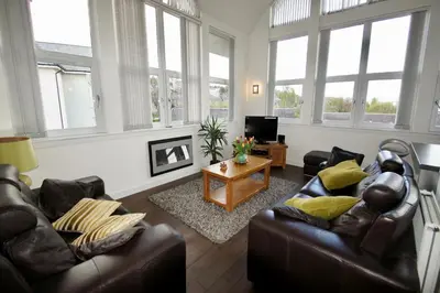 a living room with two leather couches and a table at Penthouse Apartment in Stirling