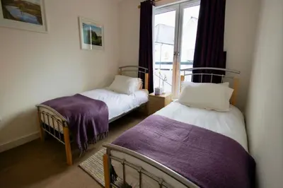 two beds in a room with a window at Penthouse Apartment in Stirling