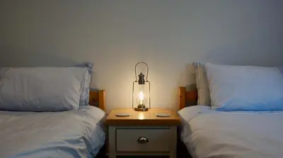 two beds with a lamp on a table between them at Ruchearn in Comrie