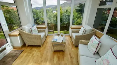 a living room with couches and chairs and large windows at View Cottage in Lochearnhead
