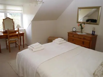 a bedroom with a bed and a desk and a mirror at Airie Farmhouse in Castle Douglas