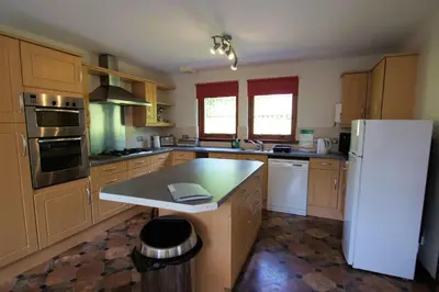 a kitchen with wooden cabinets and a white refrigerator at Osprey View in Lochearnhead