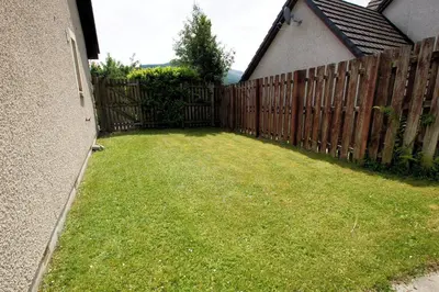 a backyard with a fence and a grass yard at Osprey View in Lochearnhead