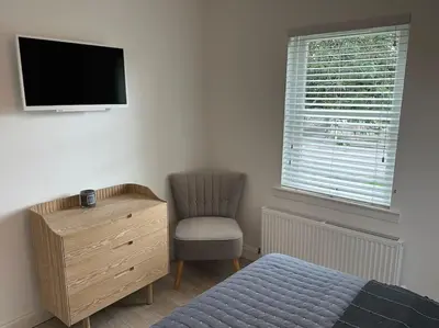 a bedroom with a bed and a chair and a television at Premium executive Apartment in Dunfermline in Dunfermline