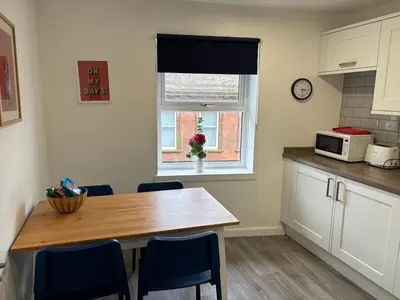 a kitchen with a table and chairs and a microwave at 16 Macgregor court, Oban in Oban