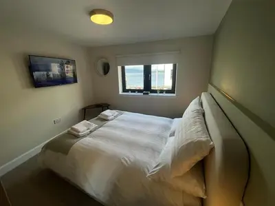 a bedroom with a large white bed with a window at Waverley Apartments - The Wedge in Gourock