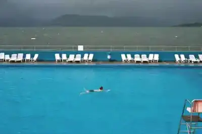 a person swimming in a swimming pool with chairs at Waverley Apartments - The Wedge in Gourock