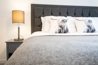 a bedroom with a bed with two dogs on the pillows at Beautiful Glasgow South Home - Pass the Keys in Glasgow
