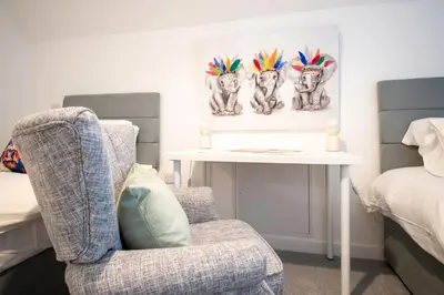 a bedroom with a chair and a table and a bed at Beautiful Glasgow South Home - Pass the Keys in Glasgow