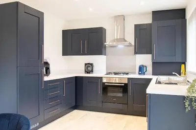 a kitchen with black cabinets and white counter tops at Beautiful Glasgow South Home - Pass the Keys in Glasgow