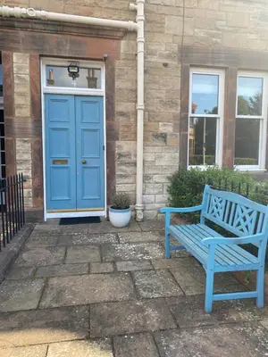 a blue bench in front of a house with a door at Tranquil Haven Murrayfield in Edinburgh