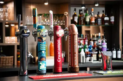 a bar counter with several different bottles of alcohol at Holiday Inn Express Edinburgh Airport by IHG in Ingliston