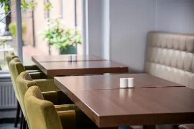 a row of wooden tables and chairs in a restaurant at Holiday Inn Express Edinburgh Airport by IHG in Ingliston