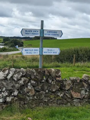 a sign in a stone wall with street signs at Loch's Heaven 67 in Kirkcowan