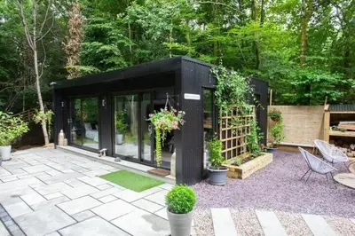 a black house with plants in a garden at The Ultimate Luss Retreat in Luss