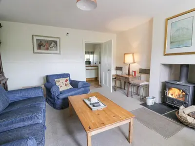 a living room with a blue couch and a wood stove at High Auchenbrack in Thornhill