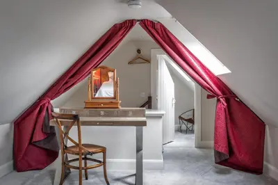 a room with a desk with a red curtain at Prince's Cottage in Thornhill