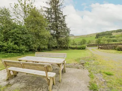 two wooden benches sitting next to a field at Prince's Cottage in Thornhill