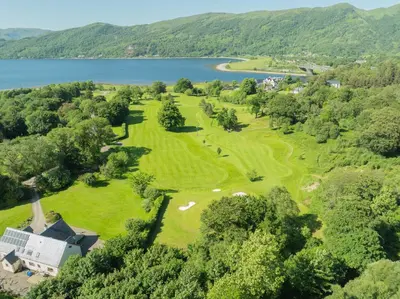 an aerial view of a golf course next to a lake at Woodlands House with Hot Tub in Ballachulish