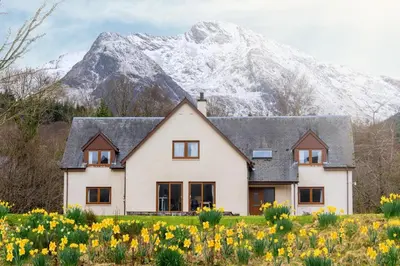 a house in front of a snow covered mountain at Woodlands House with Hot Tub in Ballachulish