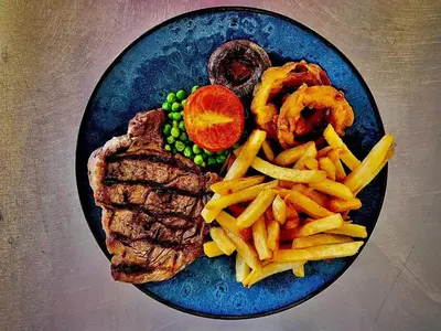a blue plate with steak and french fries and meat and onion rings at The Horseshoe in Lochgilphead